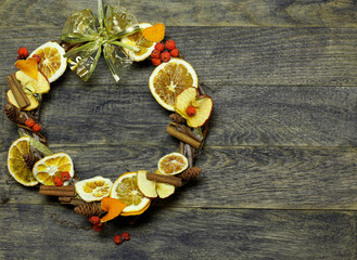 Christmas hand made craft on old wooden background. Traditional New Year`s door wreath components from dried oranges, cones. Big Copyspace frame for logo and text.