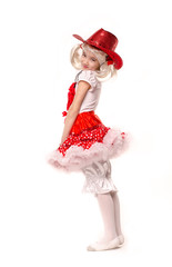 Cute little caucasian girl wearing red skirt, t-shirt with flowers and cowboy hat isolated on white background. She is dancing.
