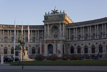 View from the street of Hosburg Palace facade in Vienna, with cars parked around and few people