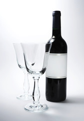 Red wine bottle and elegant wine glass, studio shot.