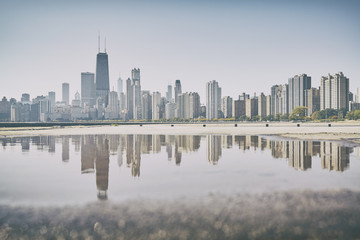 Retro old film stylized Chicago city skyline reflected in a puddle, USA.