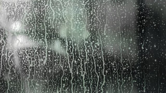 Raindrops of white water falling down on glass.