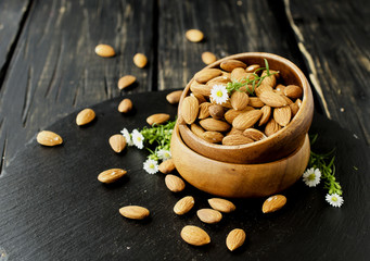 raw almonds on wooden bowl, selective focus, space for text