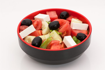 salad with cheese and tomatoes and black olives in a deep black cup on a white background