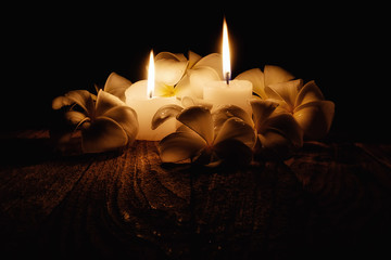 Candle light with frangipani flowers on wooden desk in black background soft focus(selective...