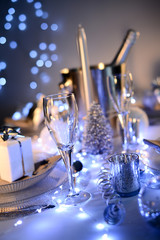 dim light white silver and blue romantic new year eve or christmas table in a luxury restaurant with champagne