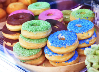 Fresh multicolored donuts behind a shop window. Sweet food.