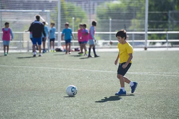 Fototapeten Niño en un entrenamiento de fútbol 7, deportes de equipo para actividades extraescolares © Angel Simon