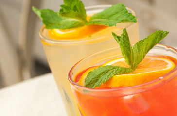Two glass transparent glass with juice and lemon on the table against the background of the chair and the sofa close-up