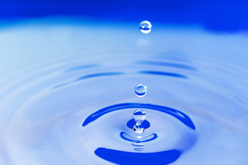 Three blue water drops  are falling on the water surface