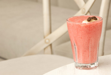 glass transparent glass with a cocktail and coffee beans and banana on the table against the background of the chair closeup