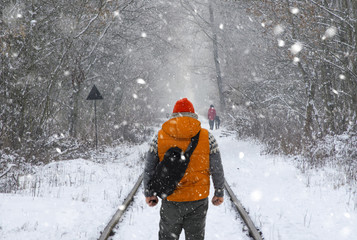 Man with backpack on the train tracks in winter - 127184249