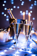 dim light white silver and blue romantic new year eve or christmas table in a luxury restaurant with champagne