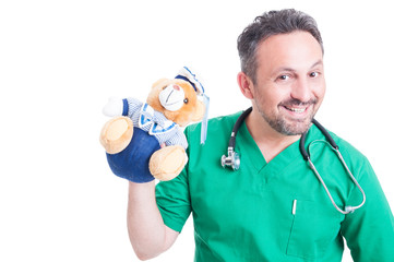 Playful doctor or pediatrician holding teddy bear