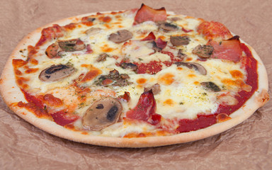 Ham, mushrooms and cheese pizza on a baking paper