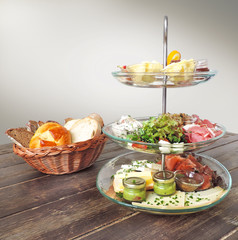 Breakfast table with fresh bread and etagere with variation of cheese and sausage.