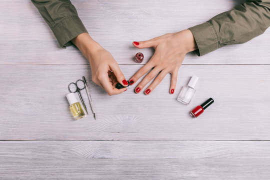 Top View Of A Woman Paints Her Nails With Red Lacquer