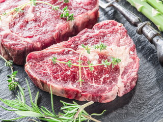 Rib eye steak with spices on the black background.