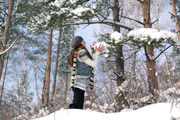 winter outdoor portrait of a cute funny positive young girl wrapped in a scarfd on a background to the Park