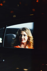 Fototapeta na wymiar Stunning blonde woman in a car at night.a woman in the back seat of a car on a background of the night fire