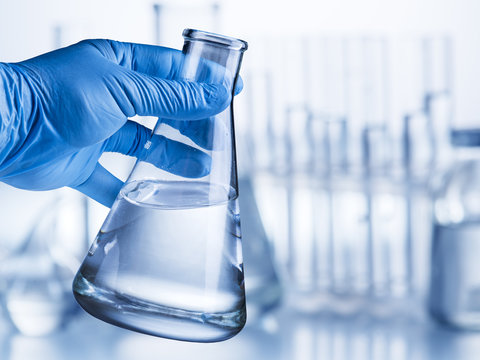 Laboratory Beaker In Analyst's Hand In Plastic Glove.