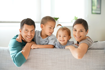 Happy family of four sitting on sofa