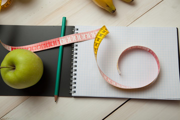 Green apples with measuring tape on a white wooden table