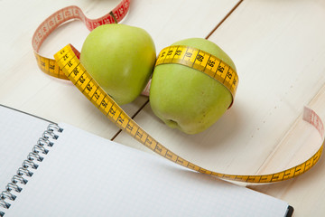 Green apples with measuring tape on a white wooden table