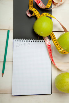 Green apples with measuring tape on a white wooden table