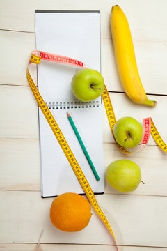 Fruits and diet plan on a white wooden table