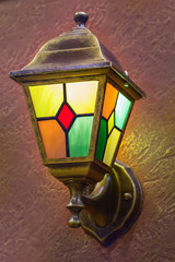 Brass lamp on the wall. Night lamp with color glass. Metal lantern.
