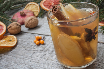 Christmas composition. Spruce branches, candy cane, warming tea with ginger and lemon,  dried oranges, grapefruit, cinnamon, star anise, pomegranates on a wooden background.