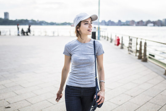 Woman with baseball cap and handbag looking at distance