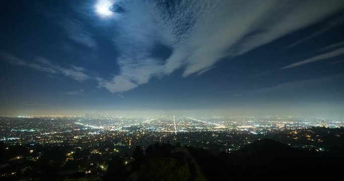 Los Angeles, California, USA - view from Griffith Observatory at City of Los Angeles facing south at clear night with moonlight and a few moving clouds - Timelapse with zoom in 