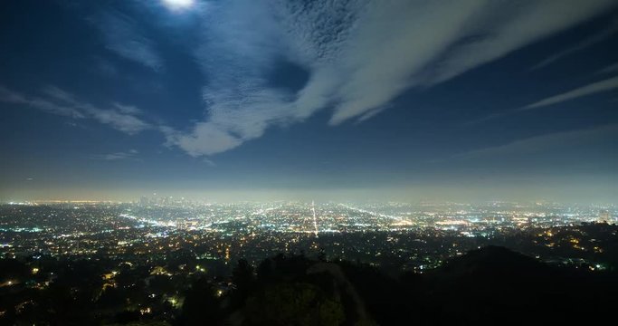 Los Angeles, California, USA - view from Griffith Observatory at City of Los Angeles facing south at clear night with moonlight and a few moving clouds - Timelapse with zoom out 