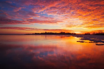 Photo sur Aluminium Mer / coucher de soleil Beautiful winter landscape with sunset fiery sky and frozen lake