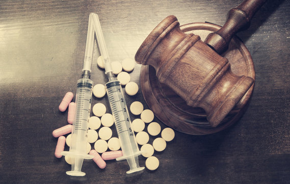 Narcotics concept, judge's gavel with drugs and syringes on wooden table