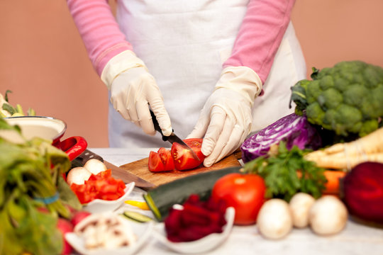 Woman with white glove cutting tomato in the kitchen