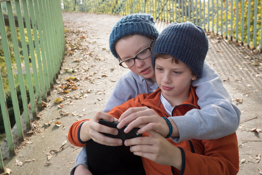 Kids staring at smartphone screen, looking over the shoulder