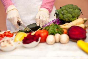 Woman with white glove slicing cucumber and preparing vegetable