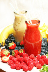 Assortment of fruit and vegetables smoothies in glass bottles with straws on white wooden background. Fresh organic Smoothie ingredients. Superfoods and health or detox diet food concept.