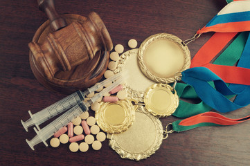 Doping in sport. Gavel, gold medals and tablets with syringes on table
