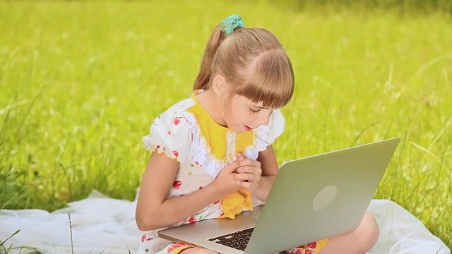 Girl prints on a laptop in a meadow