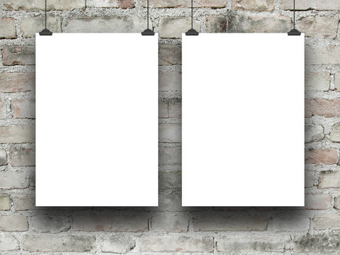 Two blank frames hanged by clips against weathered brick wall background