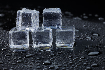 Wet ice cubes and water drop on black background.