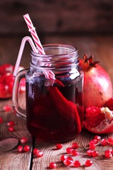 Natural pomegranate juice in a pot on the old wooden background.  Healthy food.