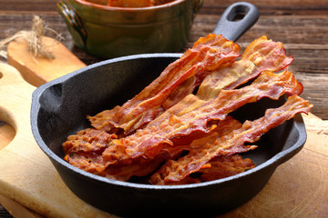 Hot fried bacon pieces in a cast iron skillet