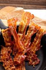 Hot fried bacon pieces in a cast iron skillet