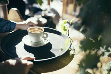 Cropped image of hands holding serving tray with coffee cup in cafe