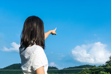 pretty young asian girl standing and point to blue sky